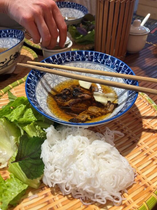 Grilled pork, rice noodles, and fresh herbs served as bún chả on a Hanoi food tour