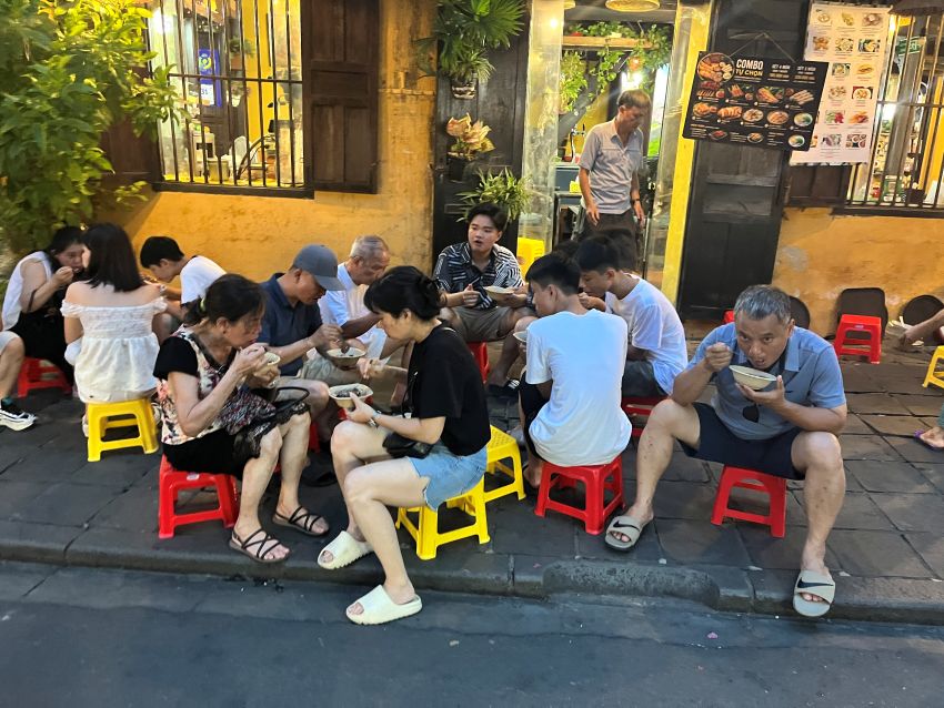 People eating on short stools in Hoi An