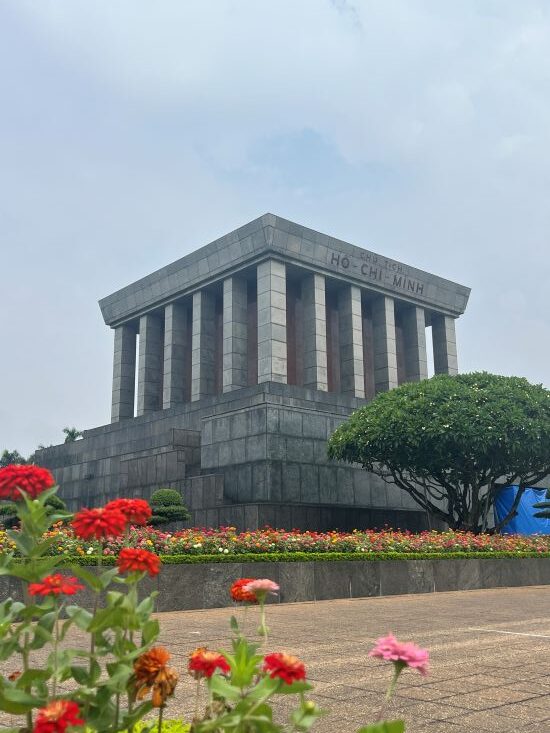 Ho Chi Minh Mausoleum with pink flowers in the foreground
