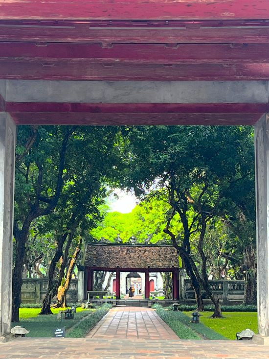 Tree-lined courtyard framed by a gateway at the Temple of Literature in Hanoi