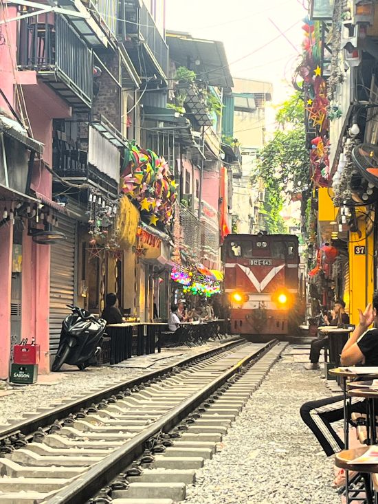 Train approaching between homes and cafés on Hanoi Train Street